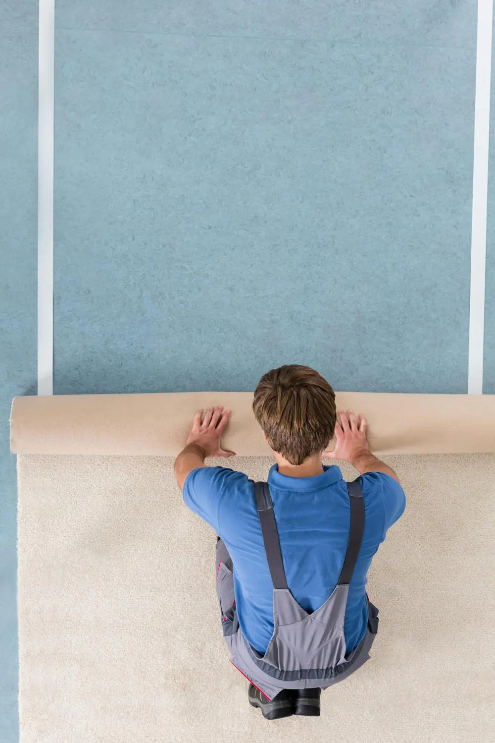 A roll of carpet being unrolled across a floor, showing the full width of the roll