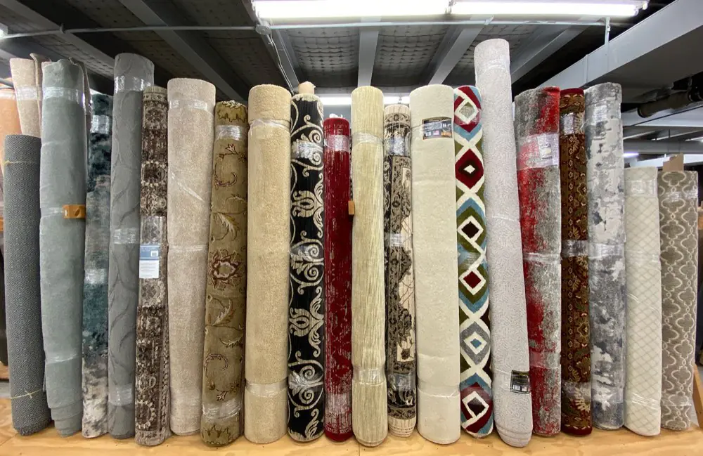 Rolled carpet and area rugs standing on the Remnant City showroom floor